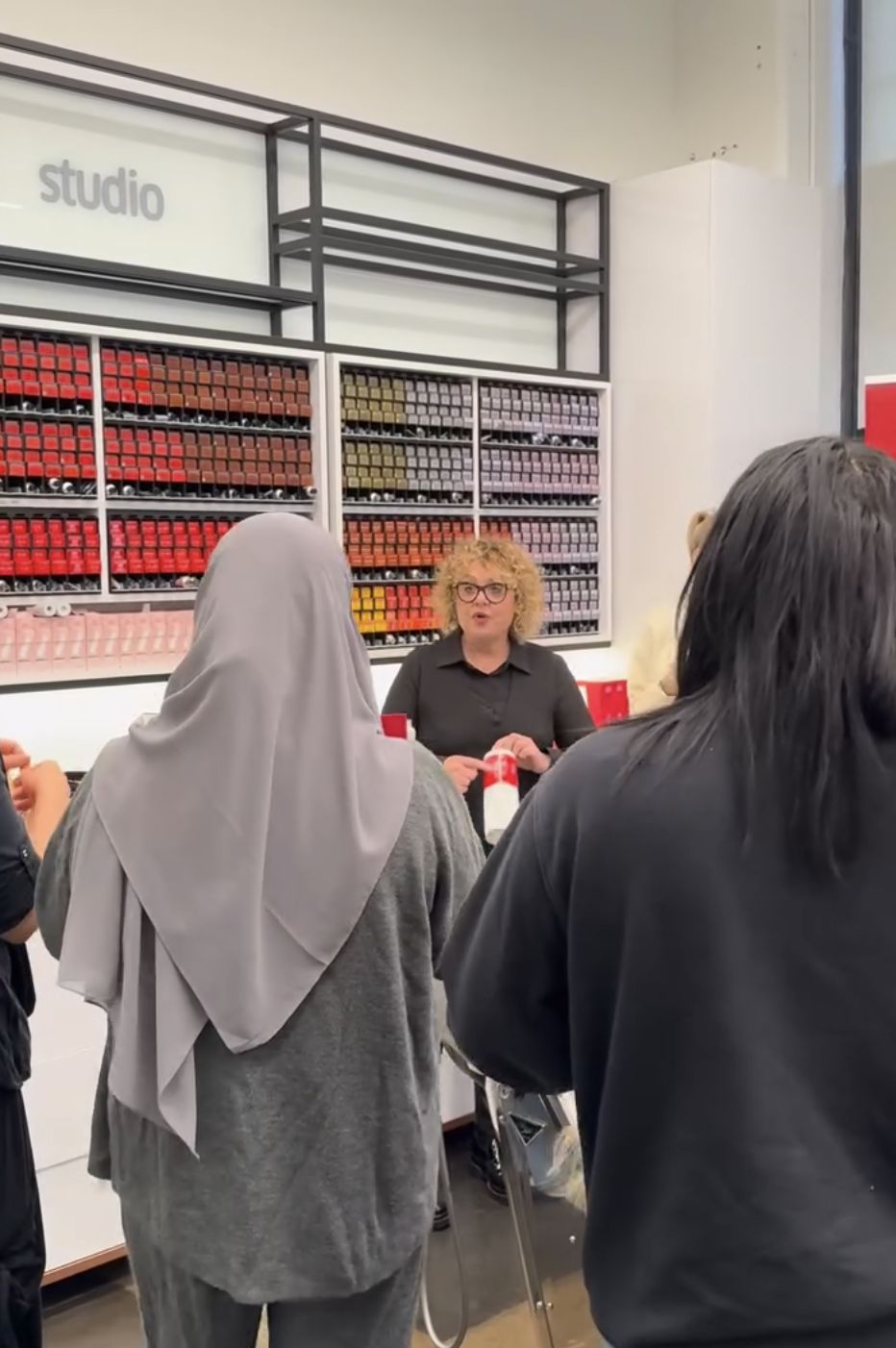 A mentor speaking with participants in a Wella studio surrounded by hair colour displays