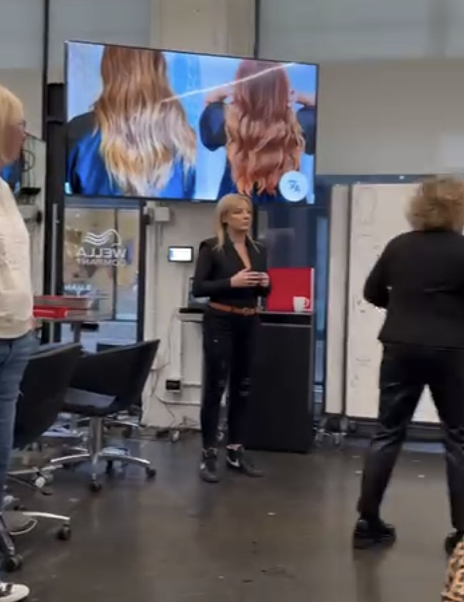 An industry mentor speaking with hairstyling participants in a Wella studio classroom